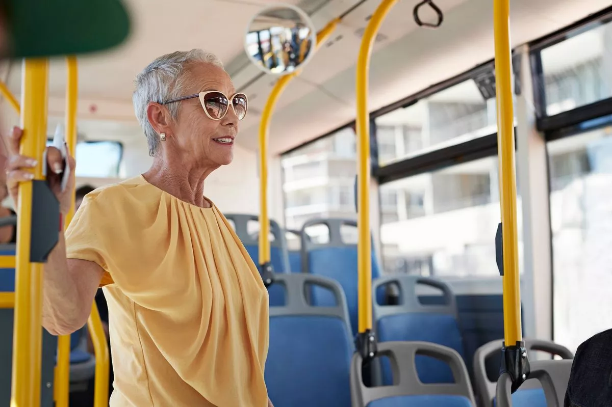 Senior woman standing up, in public bus