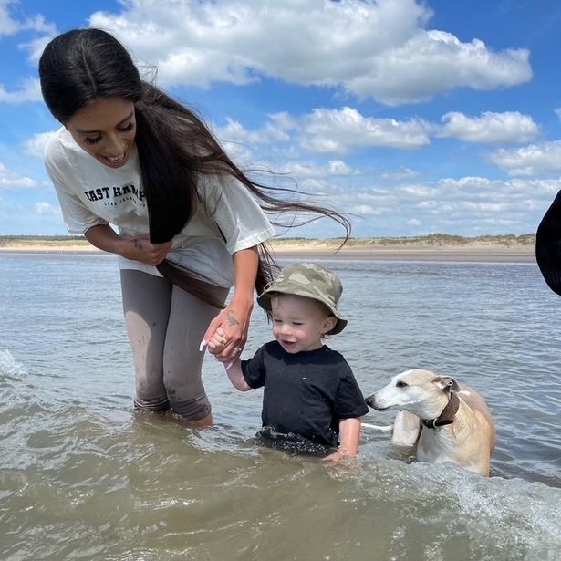 Mother with her young son and whippet dog in the sea