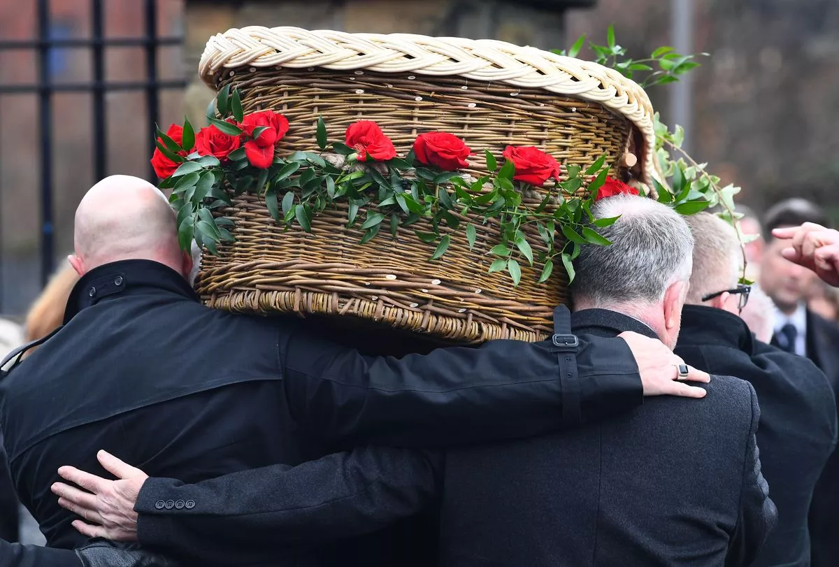 Johnny Kennedy's coffin decorated with red roses, being carried into St Francis Xavier's Church