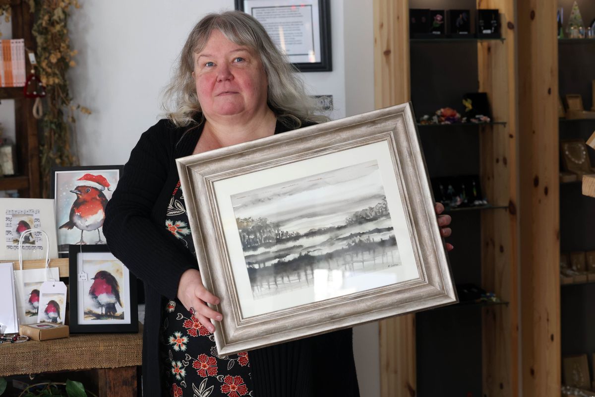 A woman holding up a black and white landscape piece