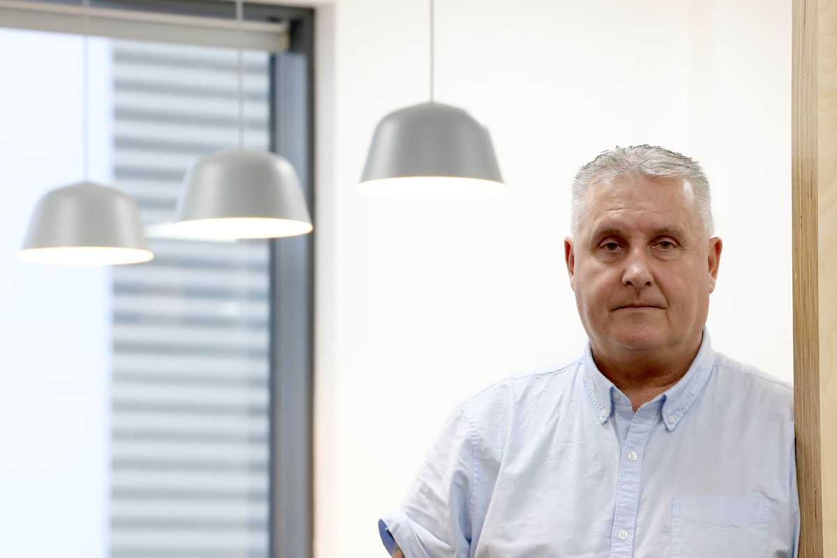 A man posing for a picture with a row of lights behind him
