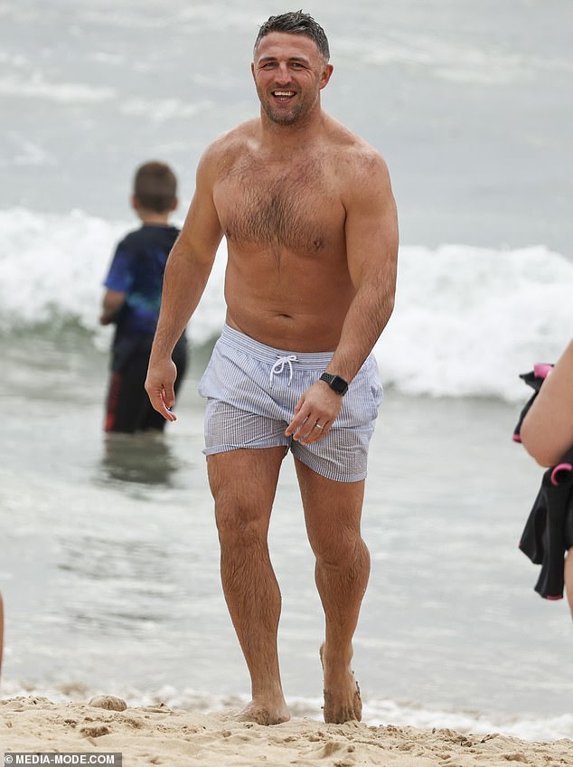 Meanwhile, Sam flaunted his famously muscular physique by going shirtless in a pair of grey boardshorts as he walked along the beach, looking relaxed and content in dad mode