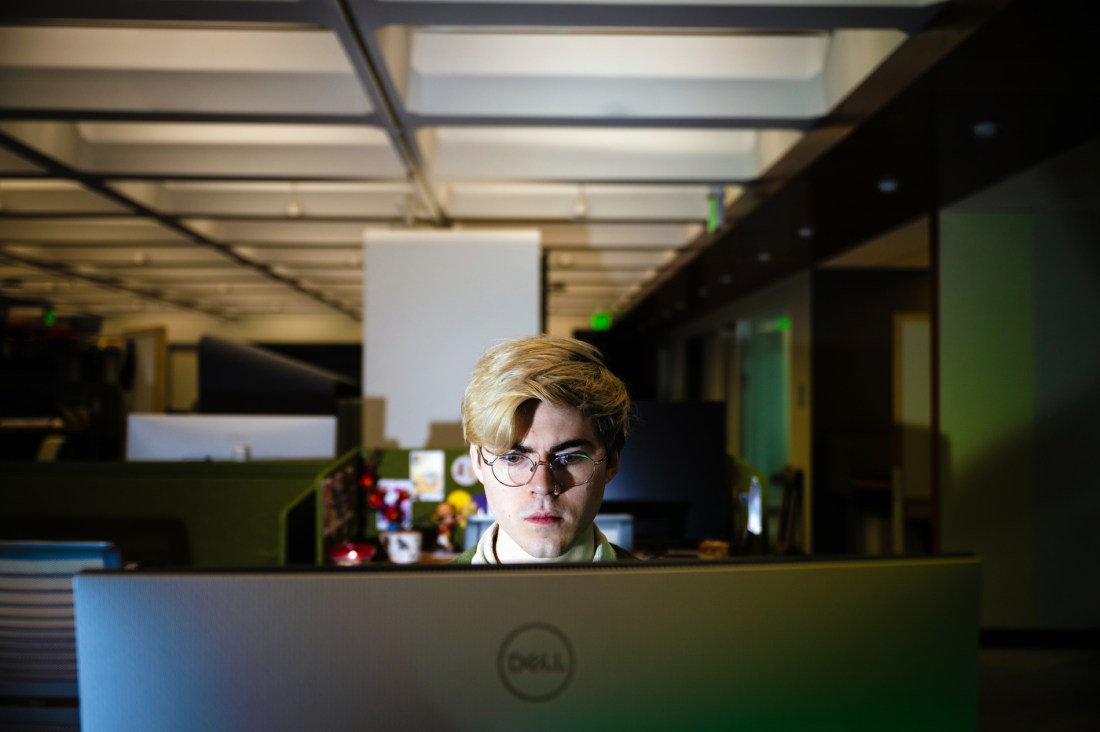 Levi Kaplan sitting in a dimly lit lab in front of a computer screen.