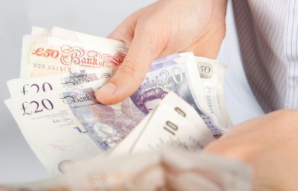 An unidentified person is holding UK bank notes 
