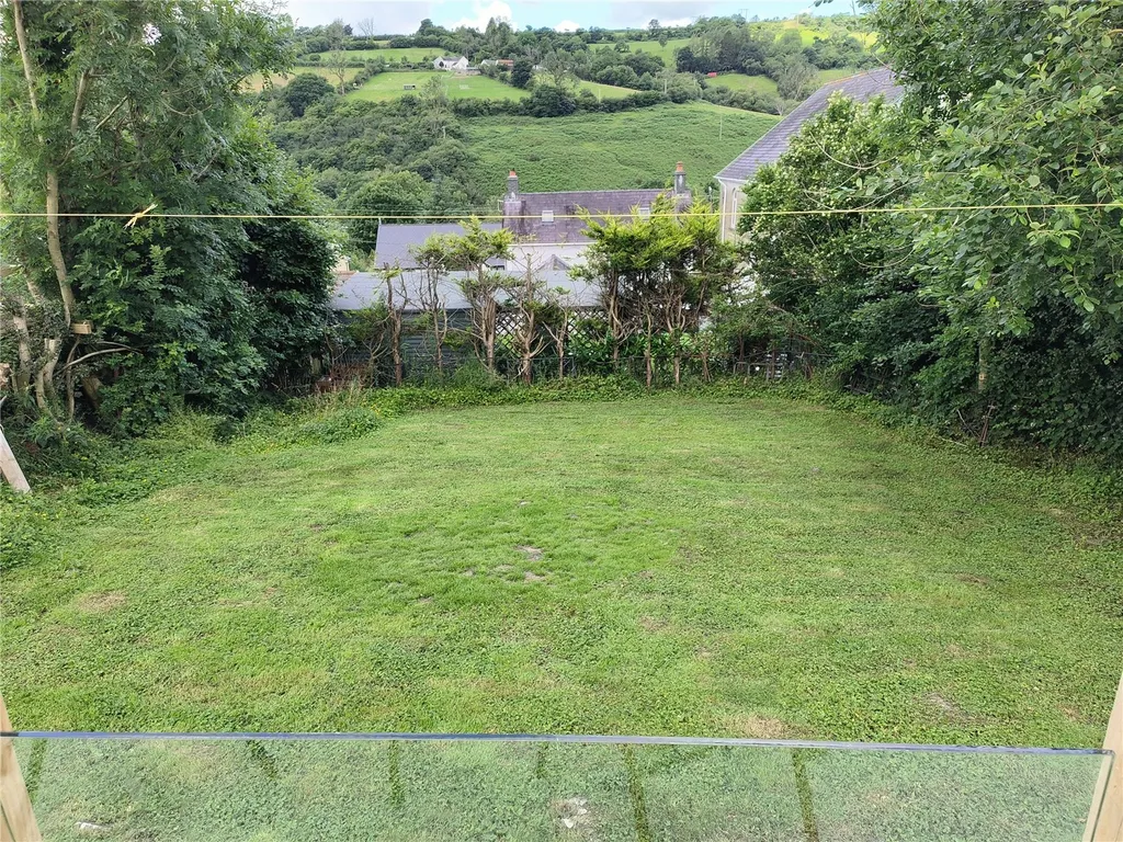 Grassy backyard with clothesline, trees, and scenic view of Carmarthenshire hills.