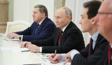 Men in suits sit at a table.