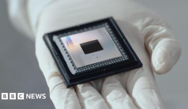 A picture of Google's Willow chip sitting in the palm of a white gloved hand. The chip - about the size of a pub coaster - resembles nested black, silver, then black squares.