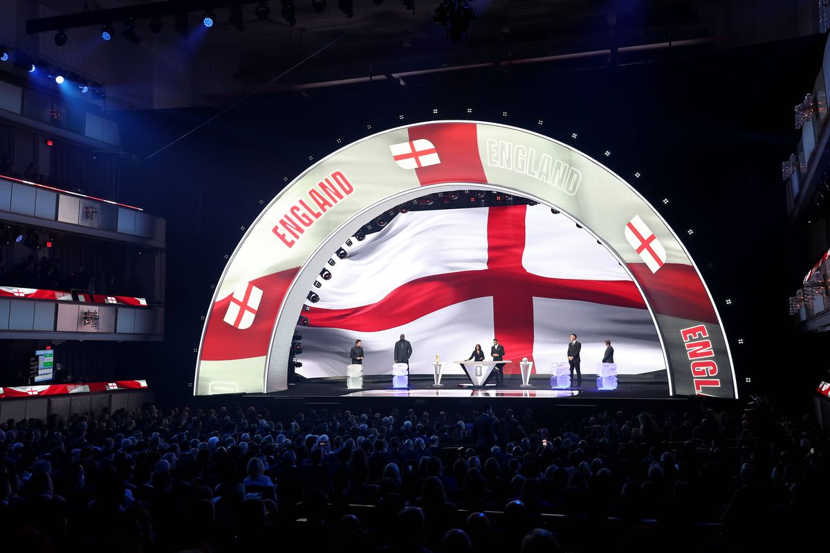 Draw assistant Tom Brady, Draw assistant Shaquille O’Neal, Co-Conductor Samantha Johnson, FIFA Legend Rio Ferdinand, Draw assistant Aaron Judge and Draw assistant Wayne Gretzky stand on stage as England is illuminated on the screen during the FIFA World Cup 2026 Official Draw