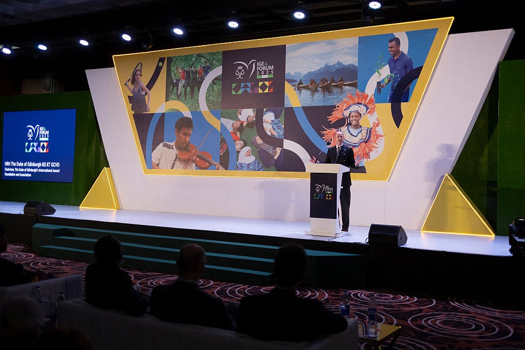 A person speaks on a stage in front of an audience.