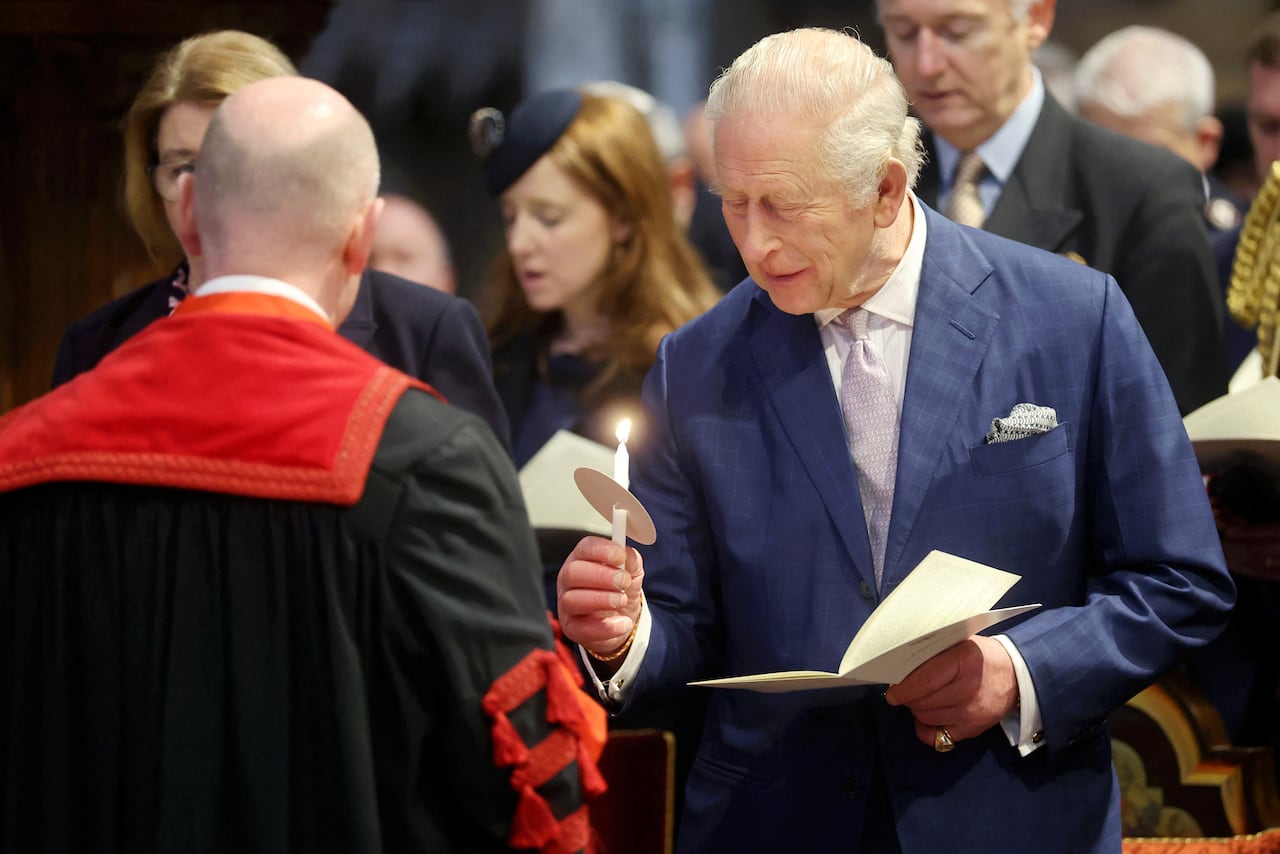A person holds a candle and an order of service during a church service.