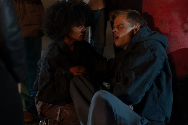Jasmine comforts Oscar on the floor on the Square as he struggles after the house fire in EastEnders
