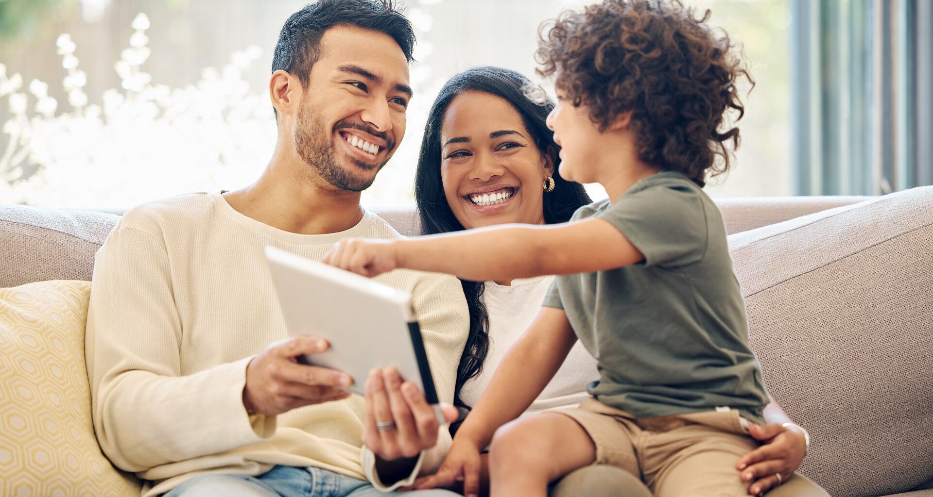 A family sits on the couch together looking happy and smiling.