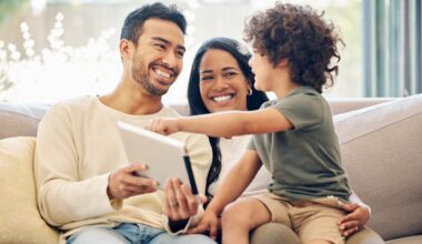A family sits on the couch together looking happy and smiling.