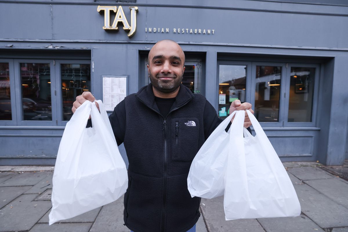 Baz Miah, owner of Taj Restaurant on Lark Lane with takeaway bags of food