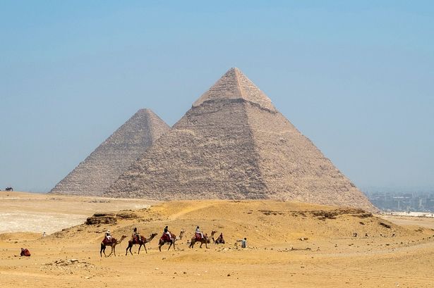 Tourists ride camels near the Pyramid of Khafre (Chephren) at the Giza Pyramids
