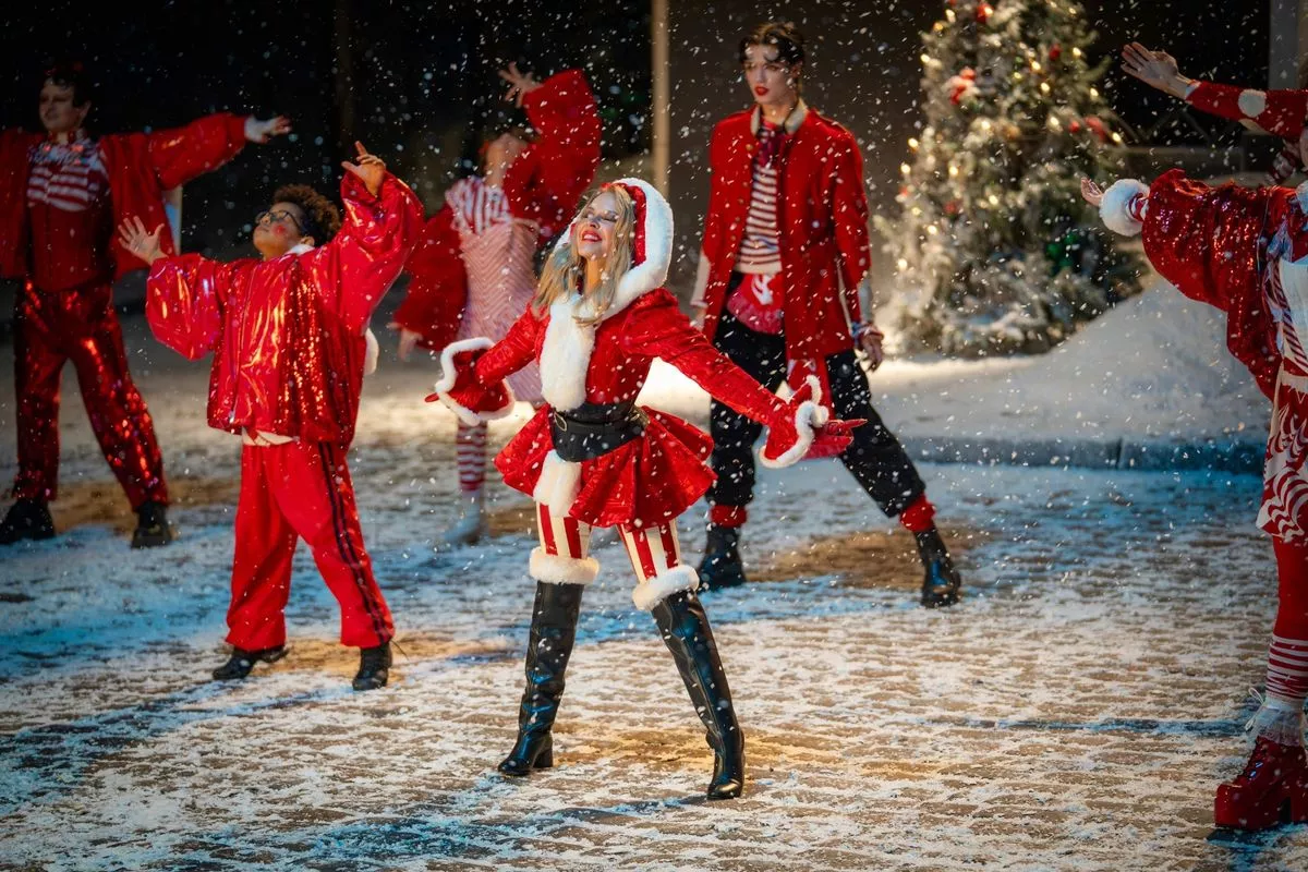 Kylie Minogu dressed in a festive outfit and standing in the snow
