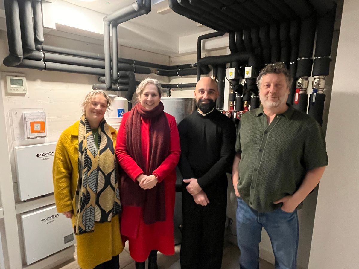 Hackney politicians and Stokey energy members stand with the priest in the generation room of the church