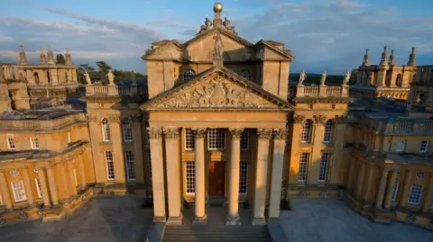 Blenheim Palace An aerial view of golden sunlight on part of Blenheim Palace, showing tall pillars beneath a carved pediment.