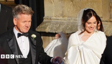 Gordon Ramsay pictured entering Bath Abbey with his daughter Holly. He is wearing a black suit and she is wearing a white dress and veil.
