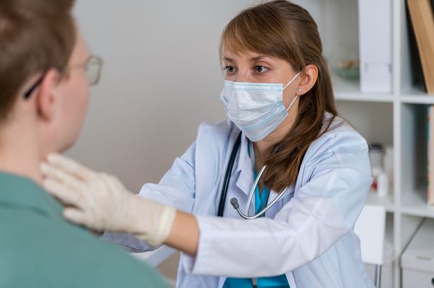 Female doctor in protective face mask checking up faceless male patient throat