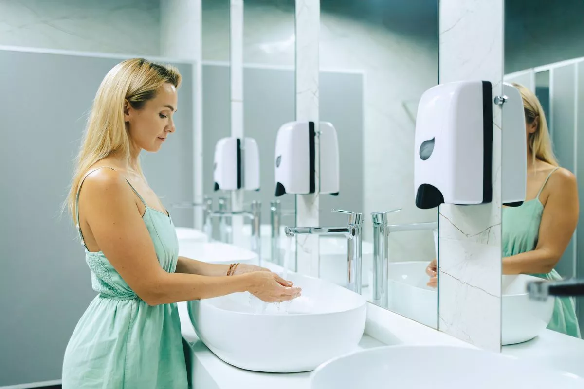 Woman washes her hands in a public bathroom