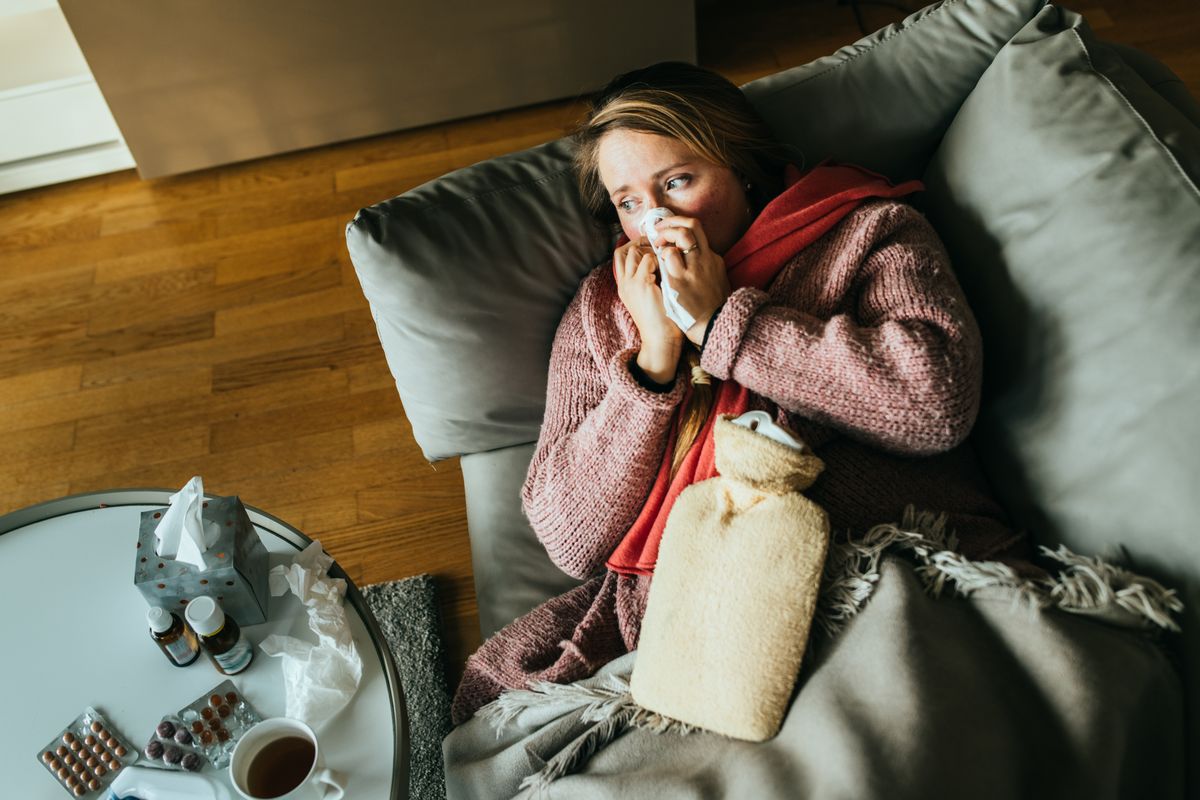 Woman lying on a sofa while having a flu and feeling sick.