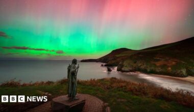 St. Crannog's statue is watching over the shoreline underneath the Northern Lights which is showcasing different colours such as green, pink and blue in the sky.
