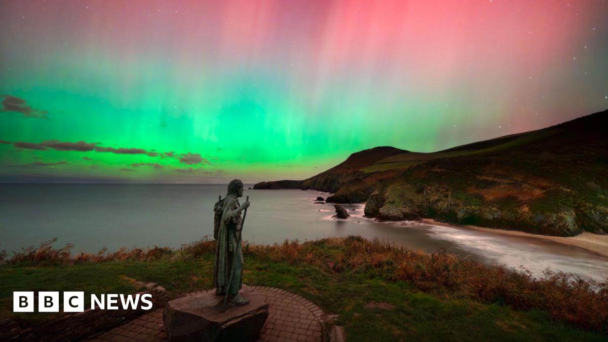 St. Crannog's statue is watching over the shoreline underneath the Northern Lights which is showcasing different colours such as green, pink and blue in the sky.