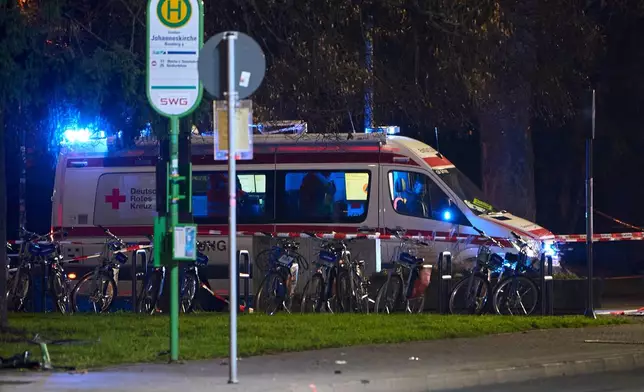 A German Red Cross (DRK) emergency vehicle stands behind a barrier tape, at the site where a car is said to have driven into a bus stop and several people were injured, according to the police, in Giessen, Germany, Monday Dec. 22, 2025. (Sascha Ditscher/dpa via AP)