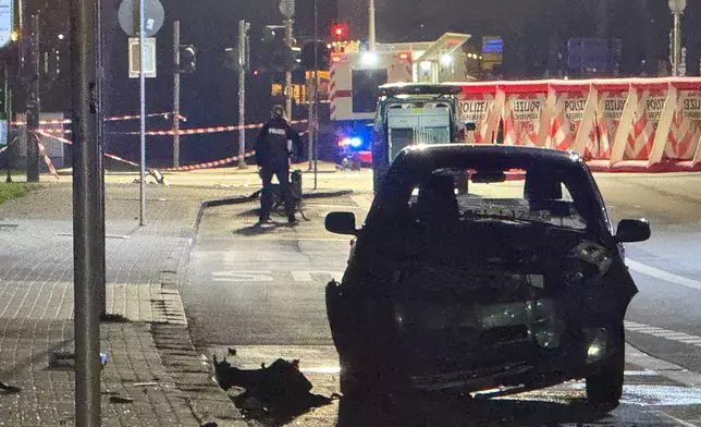 A wrecked vehicle is seen where a 32-year-old man from Azerbaijan, crashed his car into a bus stop Monday, Dec. 22, 2025, in Giessen, Germany. (AP Photo/Tom Moldoveau)