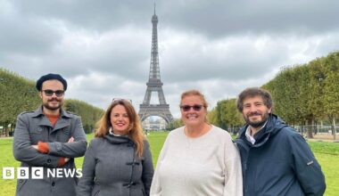 Two men and two women standing in front of the Eiffel Tower in France.