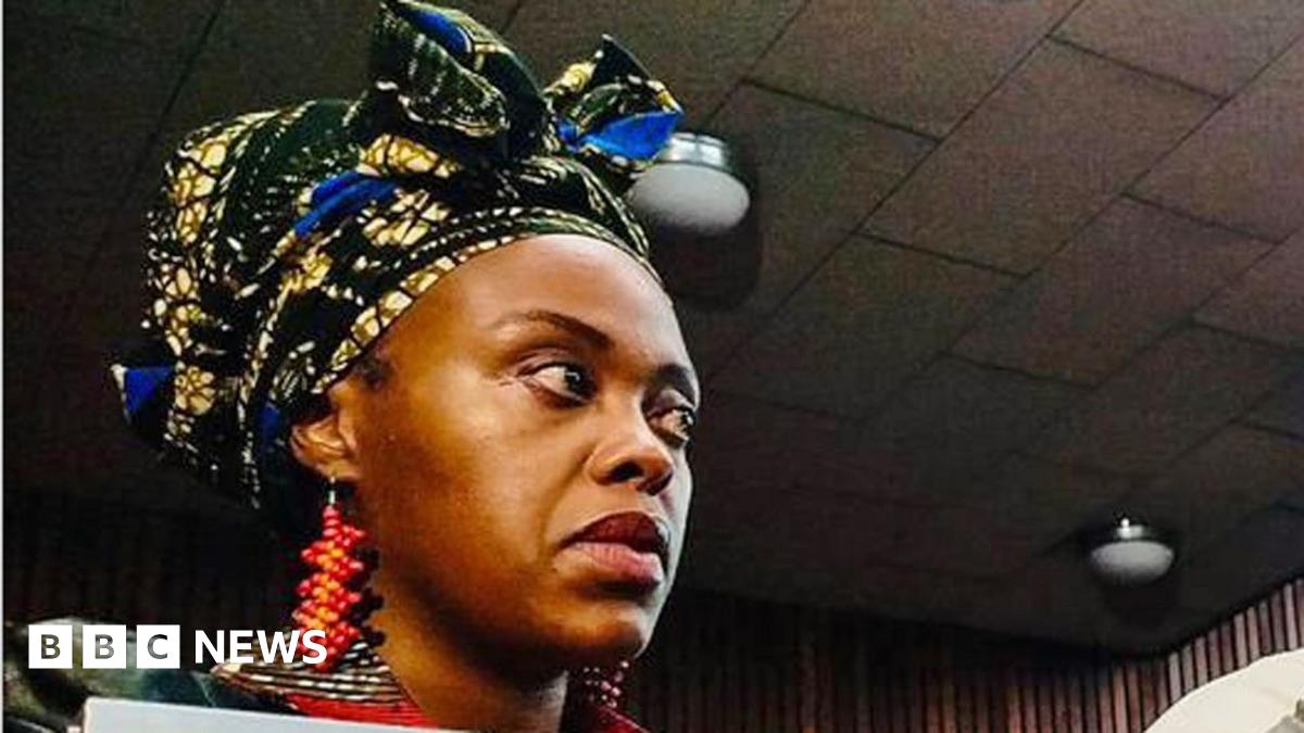 Nonkululeko Patricia Mantula, wearing a headwrap, large beaded orange, red earrings and a leather jacket look on in court.