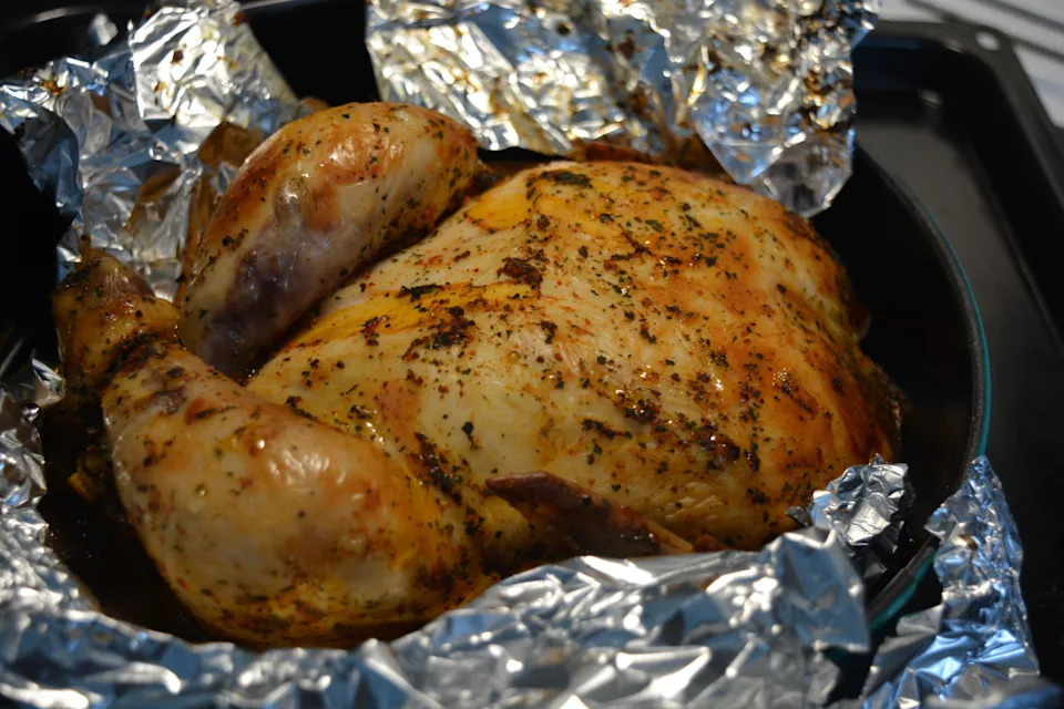 Beautiful, deliciously cooked marinated chicken in the oven. Chicken with golden, toasted skin wrapped in silver foil.