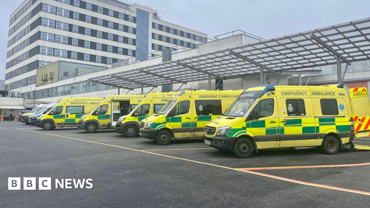 A row of ambulances are parked outside a hospital