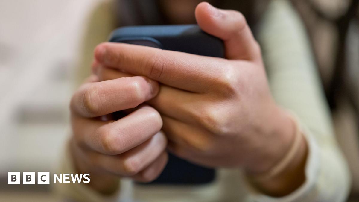 A close-up of a woman's hands clasping a smartphone in front of her.