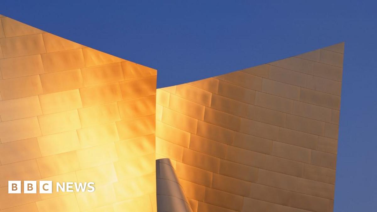 A view of the Guggenheim Museum in Bilbao, Spain. It shows the building's unique silver material, glistening in bright sunshine, around its iconic curvature.