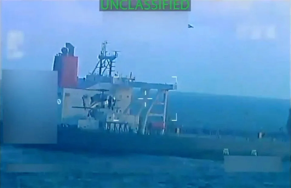 A U.S. military helicopter flies near an oil tanker during a raid described by U.S. Attorney General Pam Bondi as its seizure by the United States off the coast of Venezuela, Dec. 10, 2025, in a still image from video.