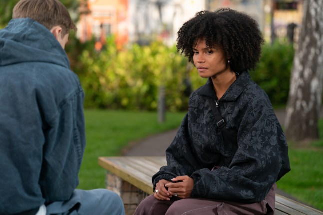 Jasmine sat on a bench talking to Oscar in EastEnders