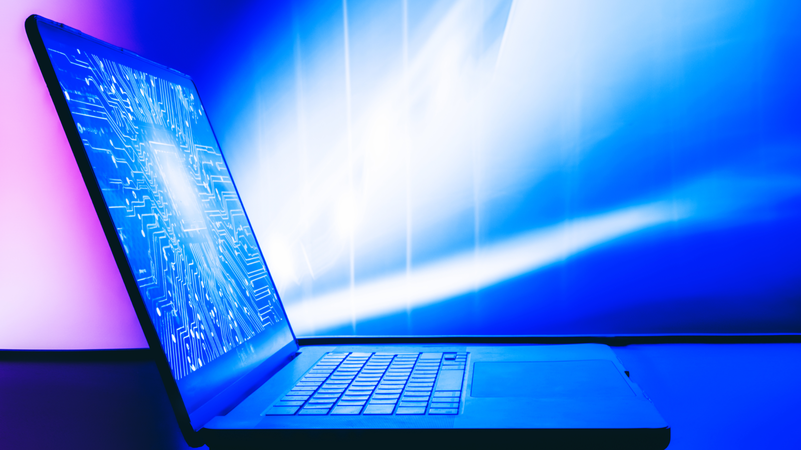 A laptop with a bright image of a digital printed circuit board on the screen.