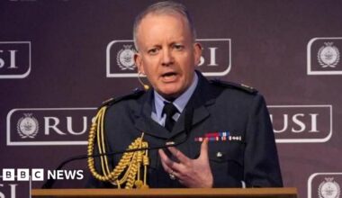 Sir Richard Knighton speaking behind a lectern. The lectern reads RUSI on the front and the background also says RUSI.