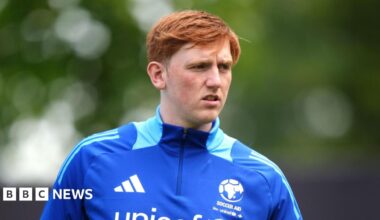 Angry Ginge wear a blue soccer aid half zip top which has lighter blue markings on the neck