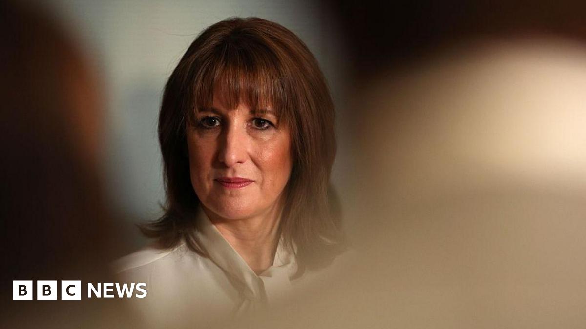 Rachel Reeves, dressed in a white blouse, can be seen in focus between the heads of an audience