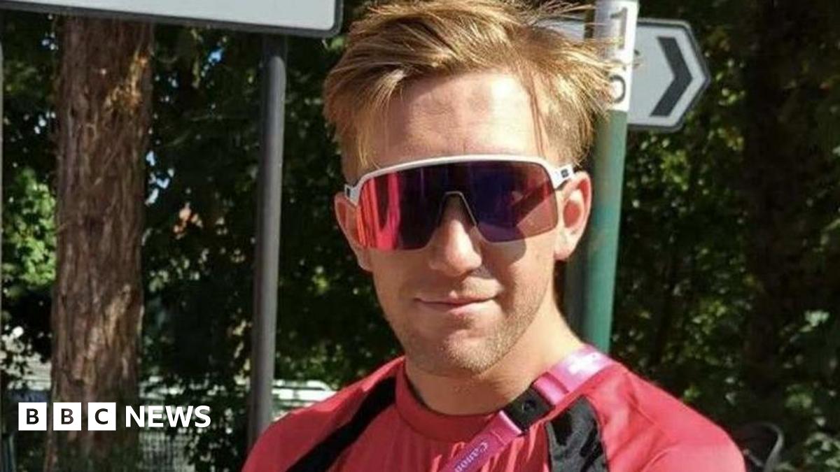 A smiling man wearing sunglasses and a red top.