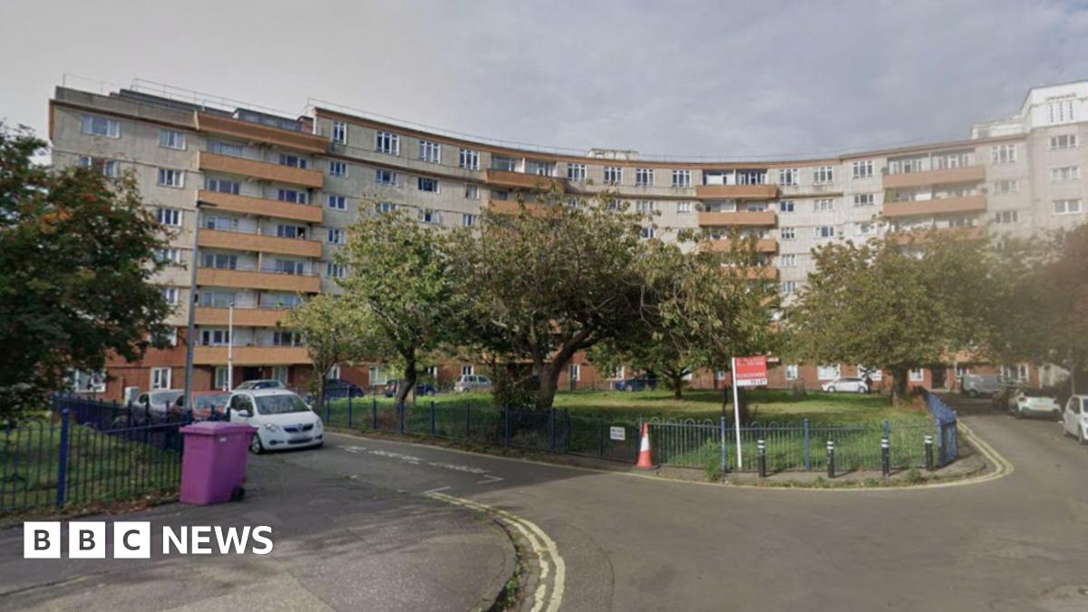 A block of curved flats which are mainly white with orange balconies.
