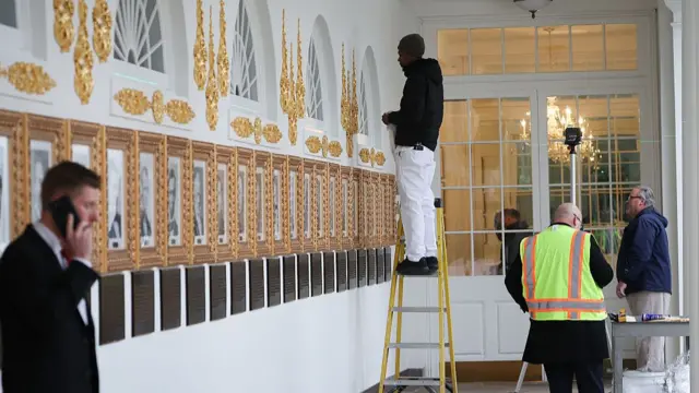 Workers install embellishments above portraits of former U.S. Presidents and newly installed plaques summarizing their legacies as interpreted by the Trump White House along the colonnade, or the “Presidential Walk of Fame”
