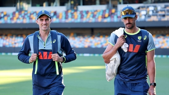 Pat Cummins and Mitchell Starc walk together before a training session at The Gabba.(AFP)