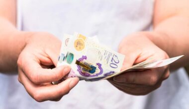 Close-up as a woman counts out modern British banknotes.