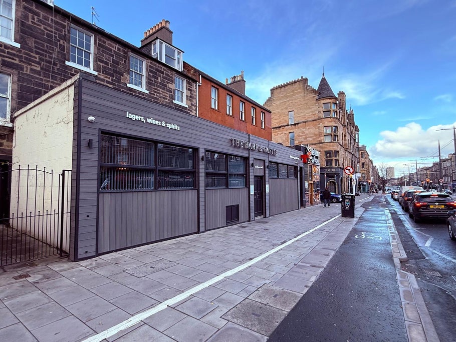 Exterior view of The Hary & Castle building with "lagers, wines & spirits" sign and street.