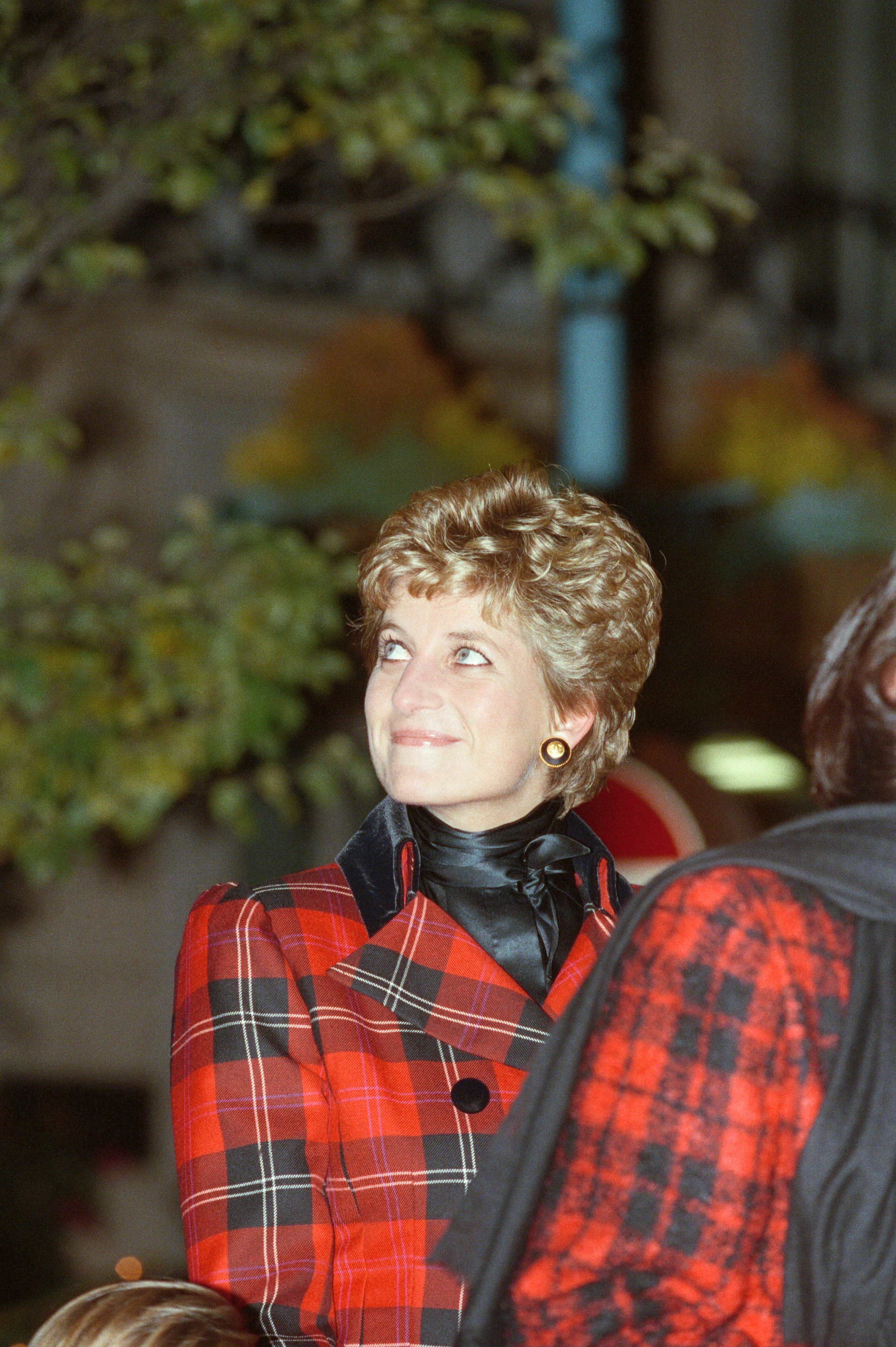 Princess Diana in a red plaid blazer smiling