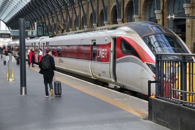 Passengers walking on a platform with an LNER train on the background.
